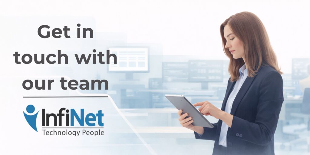 Flat-style illustration of a woman in business attire reviewing information on a tablet. She’s positioned in a quiet, professional IT office with digital displays behind her. Left side features the message: “Get in touch with our team.” InfiNet logo included.